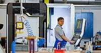 Ein Mann bedient eine CNC-Maschine in einer Werkstatt.