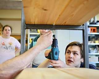 Zwei Personen arbeiten zusammen mit einem Akkuschrauber an einem Holzprojekt.