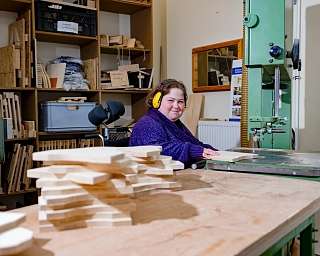 Eine Frau arbeitet in einer Holzwerkstatt mit Holzstücken.
