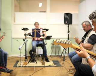 Vier Musiker spielen gemeinsam in einem Proberaum.